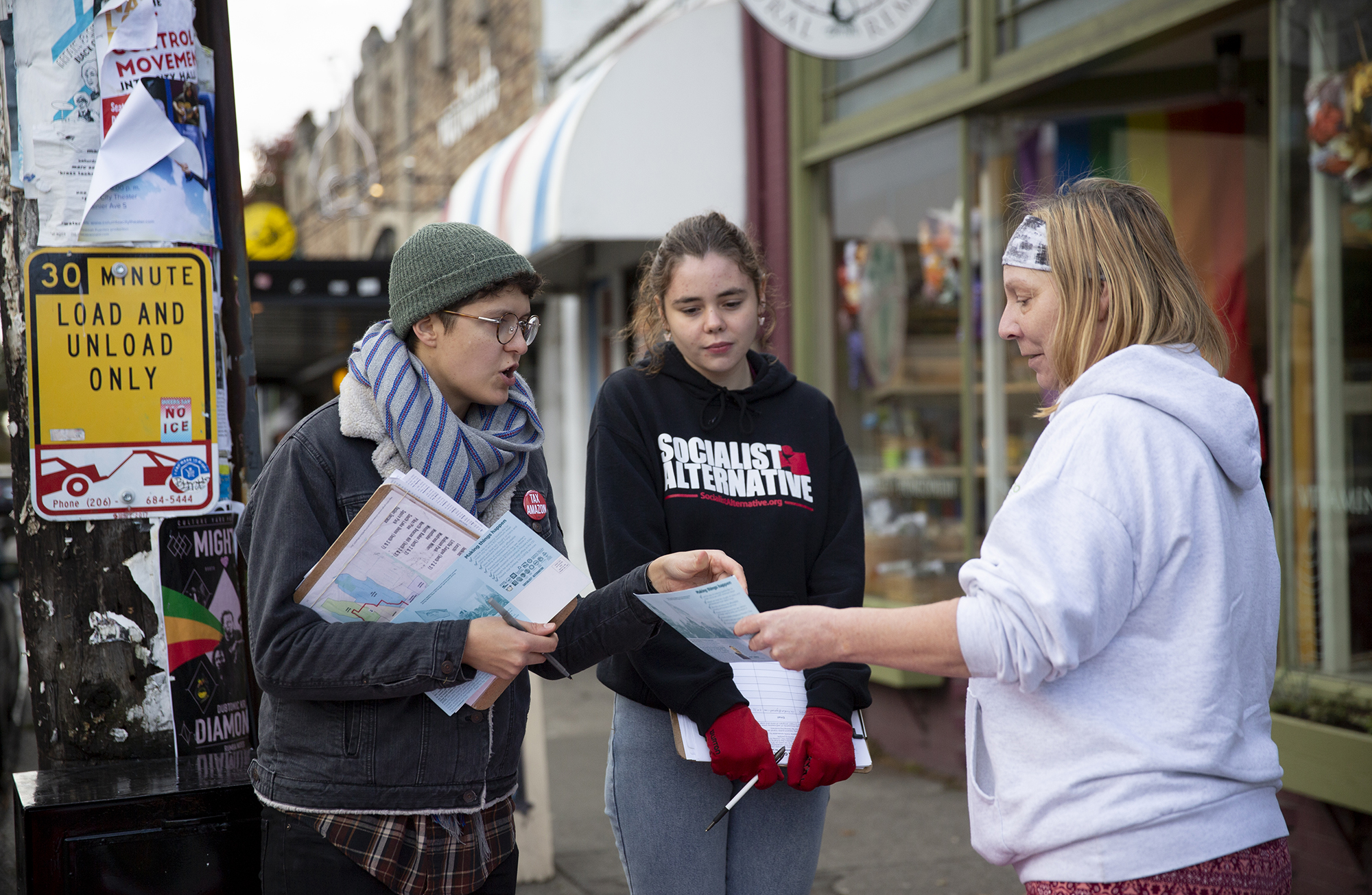 Two volunteers with the Sawant campaign talk to a person on the sidewalk.