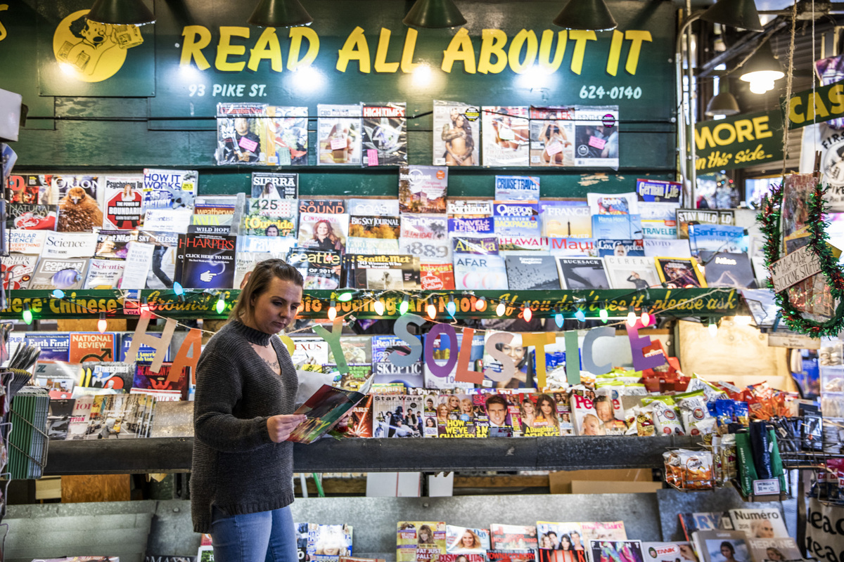 Someone reads a magazine at a news stand