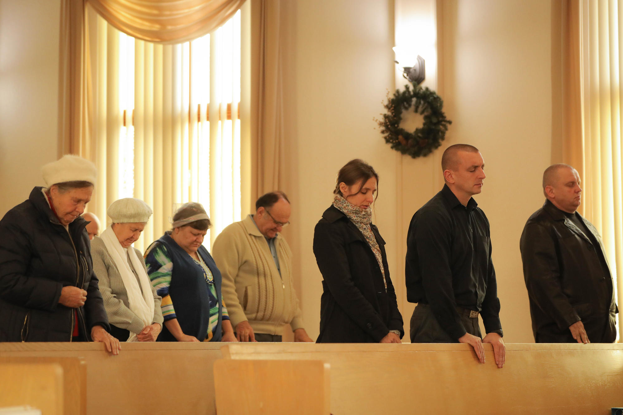 People stand in church pews and pray 
