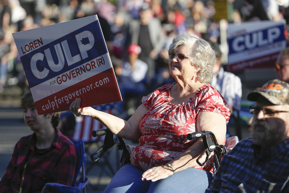 A woman holding a Culp sign sits and watches from the crowd