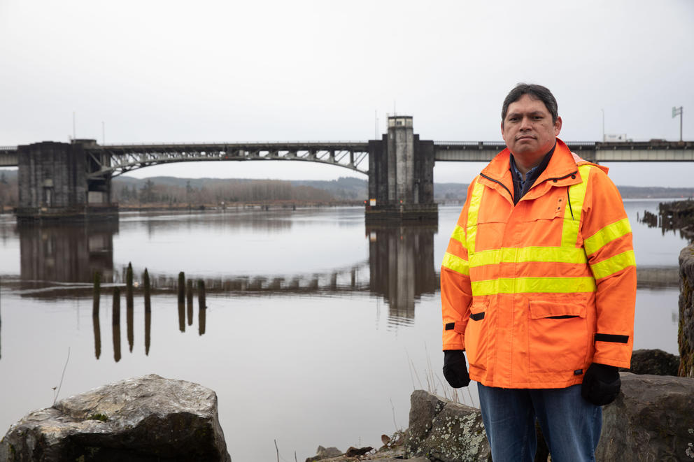 In a bridge orange jacket, Roman Peralta stands alongside the Chehalis River Bridge.