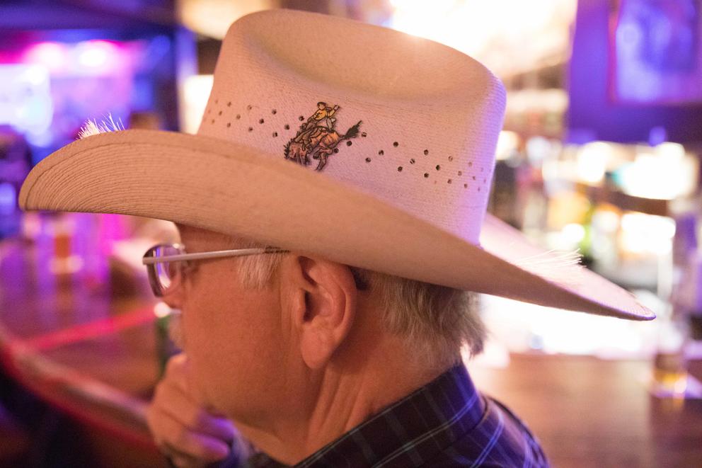 Jim Carden, a regular who has been visiting the bar for decades, sits on a barstool wearing his cowboy hat and watches dancers on the floor at Little Red Hen. 