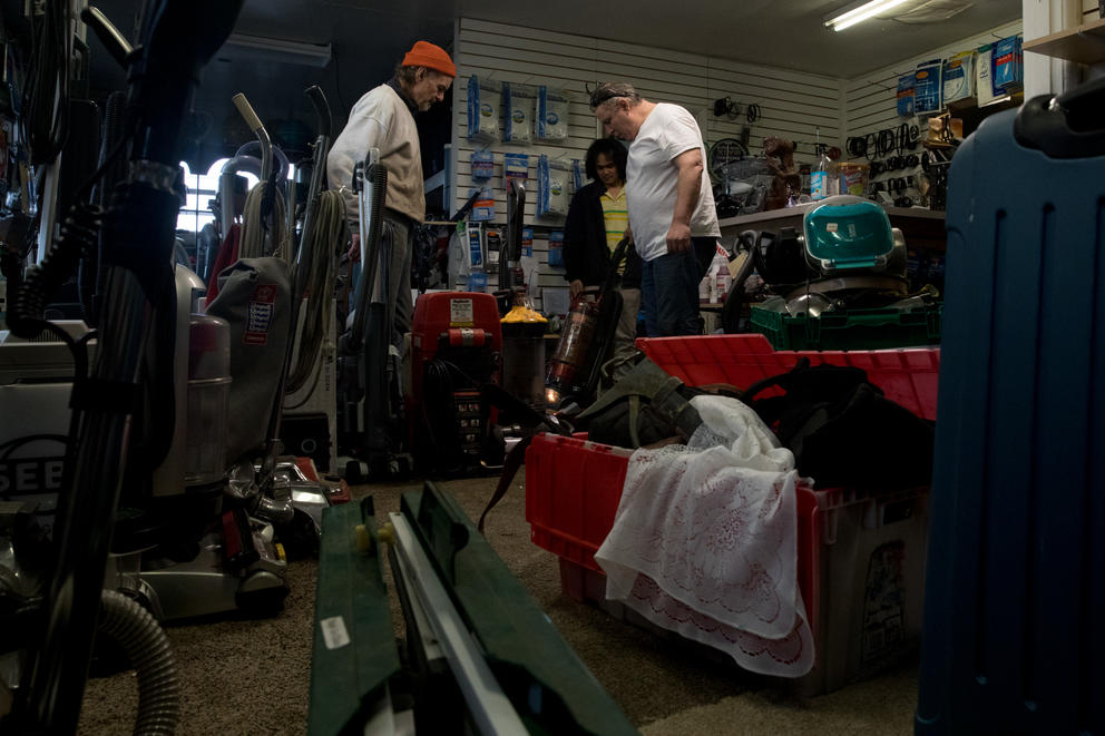 (From left) Long time customer Mark De Benedetti, employee Ogie Estrella and co-owner Guy McNally survey a vacuum at The Vac Shop in Seattle's Georgetown neighborhood, Nov. 16, 2018.