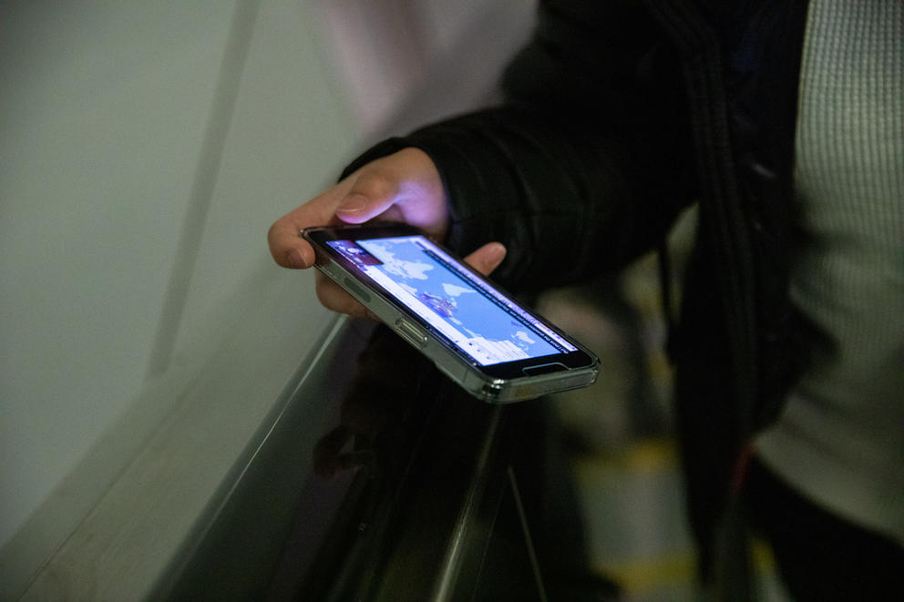 A hand holding a smartphone with a world map on its screen
