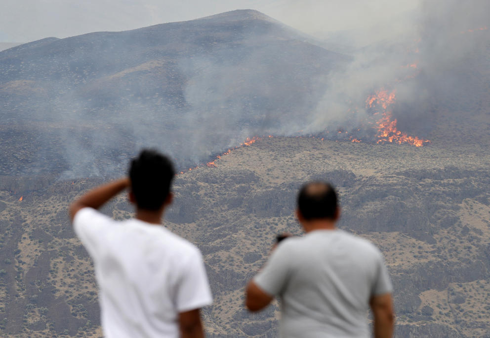 Two onlookers see a wildfire on a hillside near Vantage, Washington.