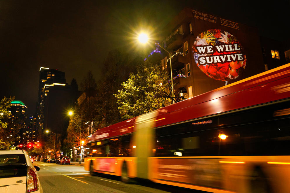 A mural on a building's side reads "We Will Survive"