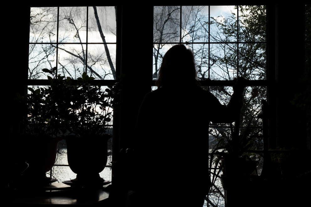 A silhouette of a woman looking out a window