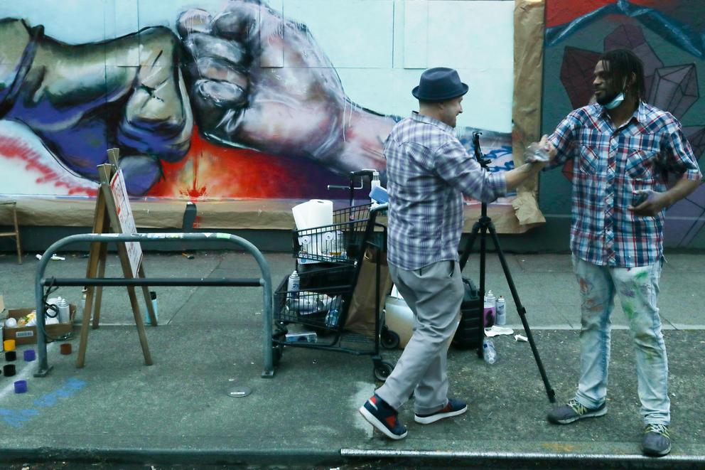 two men painting a mural of a fist bump