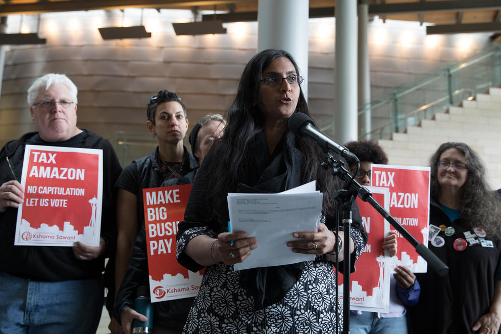 Councilmember Sawant speaks before supports holding signs reading “Tax Amazon”