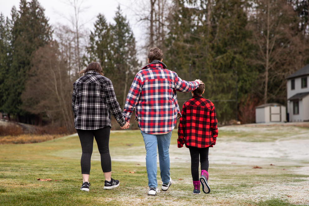 The Cofer family walks away from the camera toward the treeline, all are wearing plaid jackets