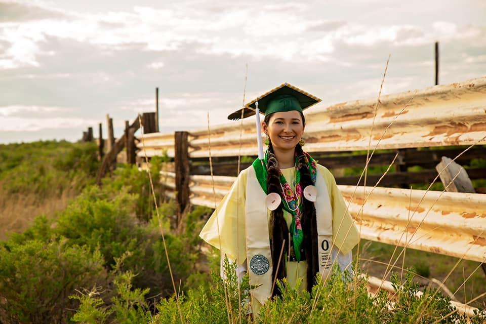 Allyson Alvarado, who goes by Tayksíki, wears her graduation cap and gown from the University of Oregon