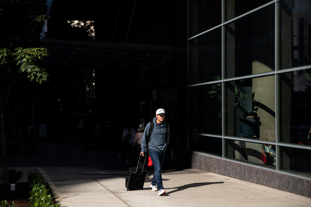a man walks with his luggage from shadow into light in downtown seattle