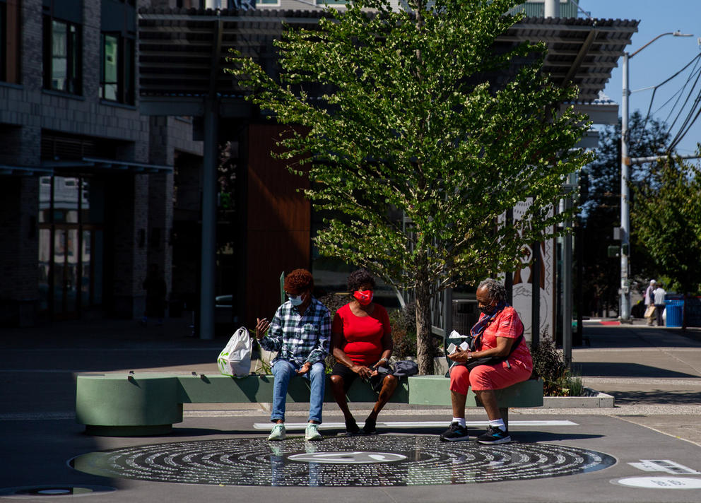 Three women sitting on a bench made from green stone