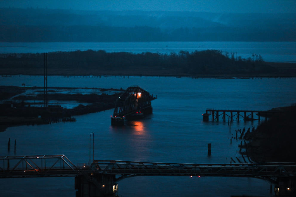 A blue hour view of a river, bridges and an island cross the frame