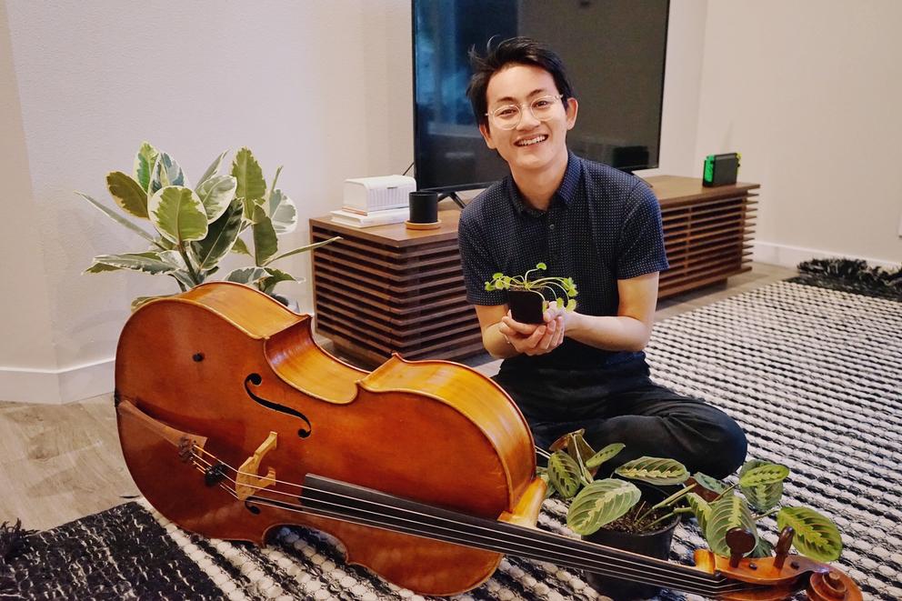 Nathan sits happily with cello and plants
