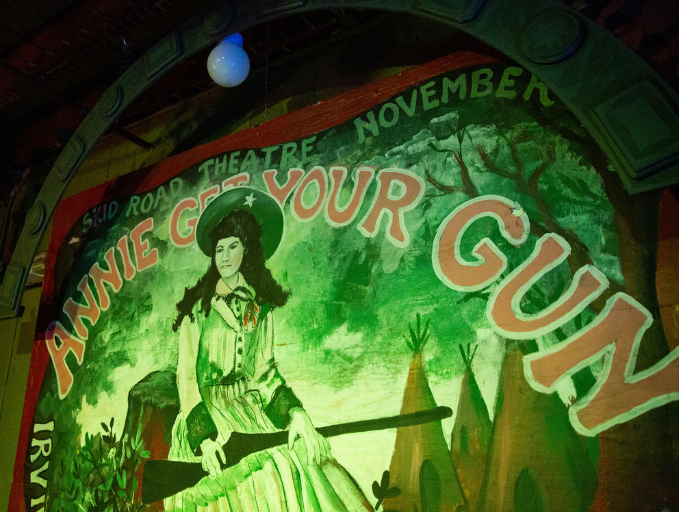 Painted mural depicting a woman with a shotgun reads "Annie Get Your Gun"