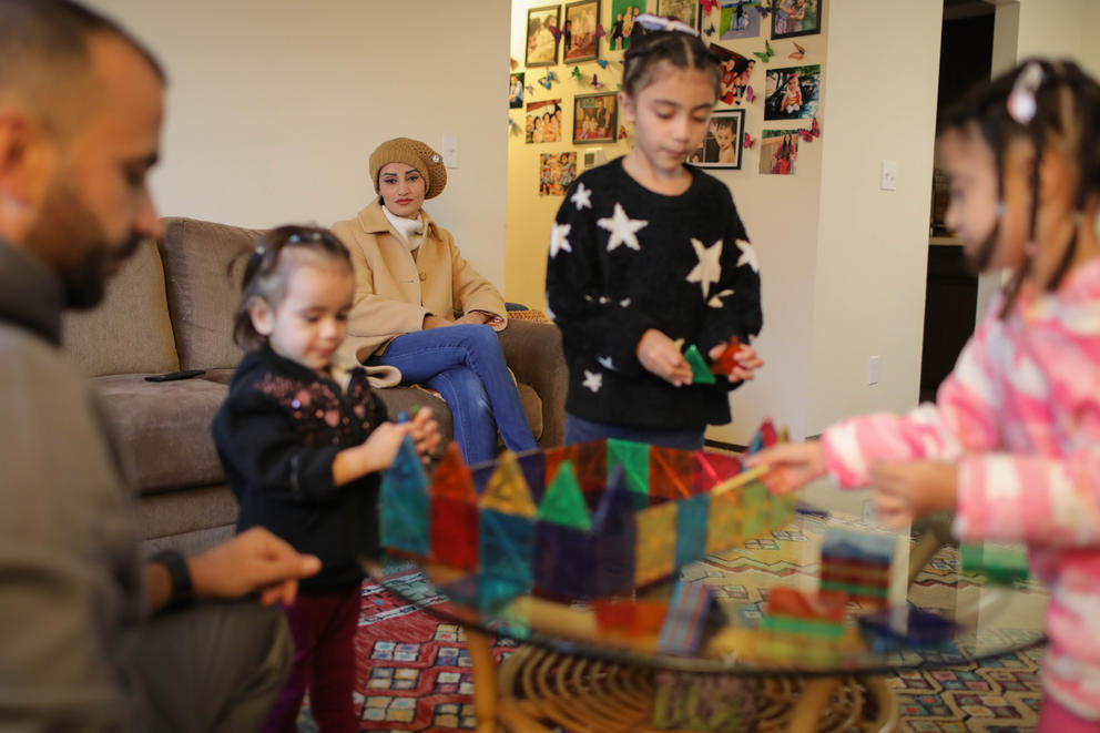 Fatima Al Noori watches from the couch as her husband Reshad plays with their three daughters at home
