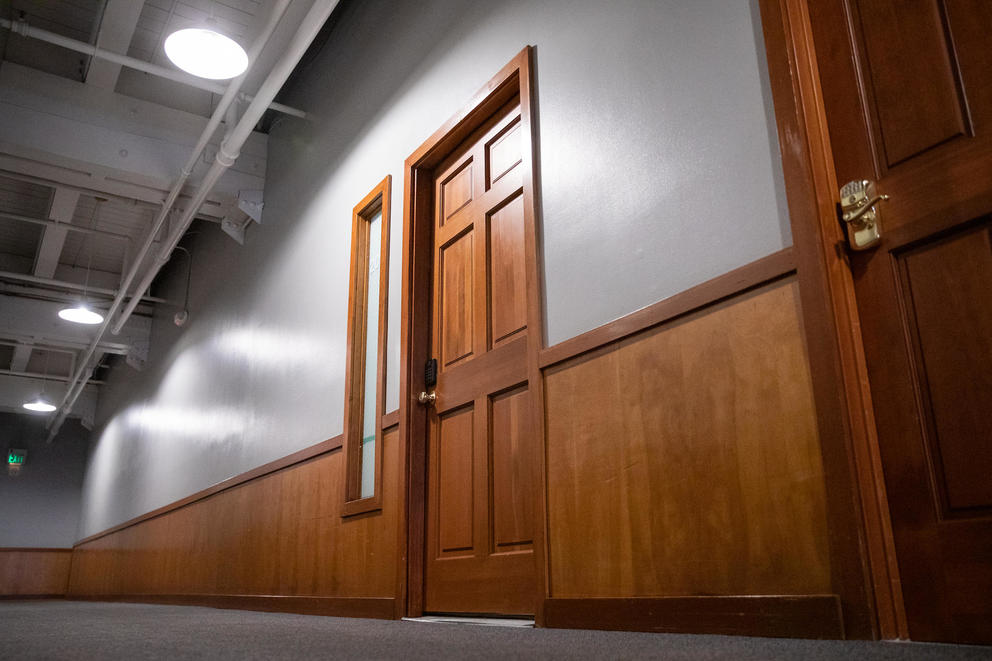 A wooden door is closed in the hallway of an office building