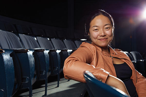 photo of a woman sitting in theater seats and smiling at the camera