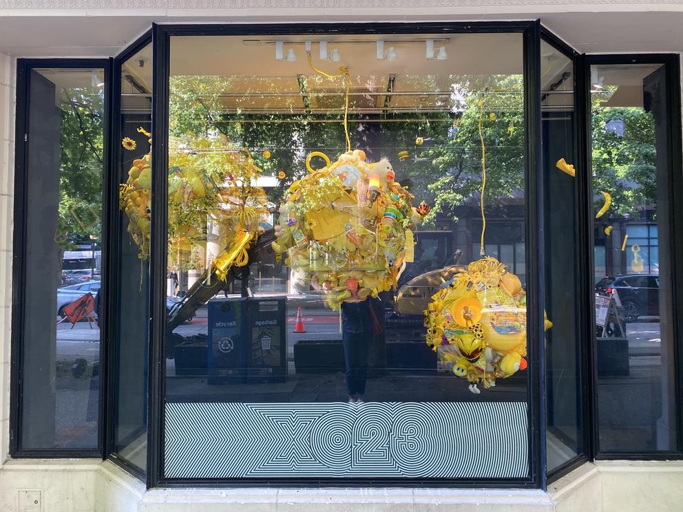store window with three large yellow spiky balls hanging from the ceiling