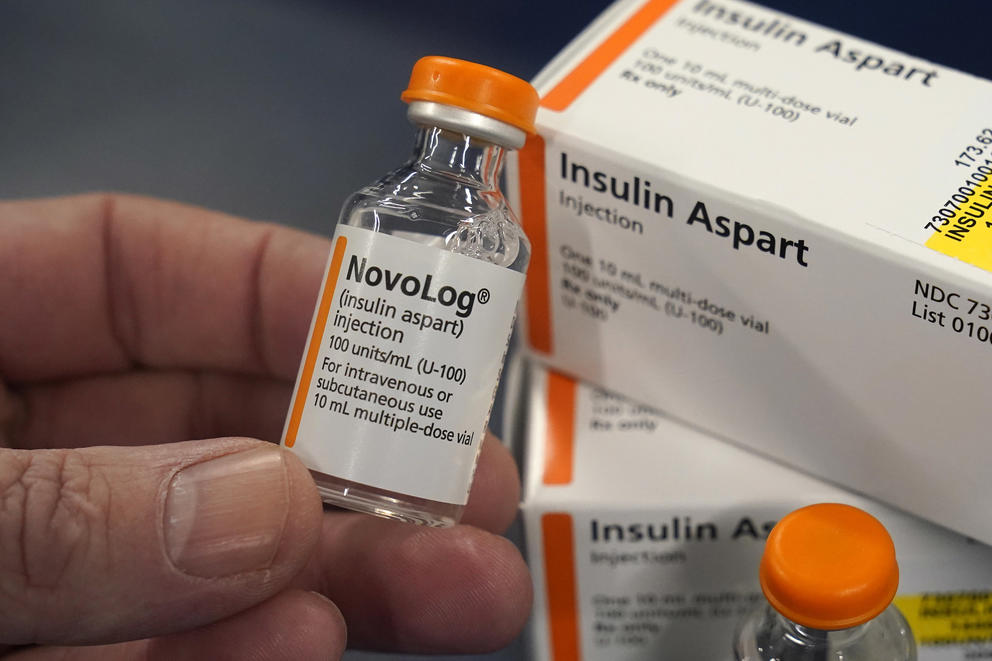 A close up of a hand holding a vial of insulin