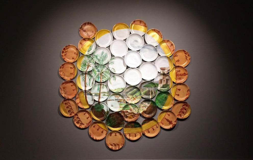 a wall installation of an idyllic island scene painted across paper plates