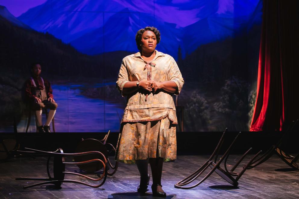 a Black woman onstage in a theatrical performance, wearing period clothing and looking worried