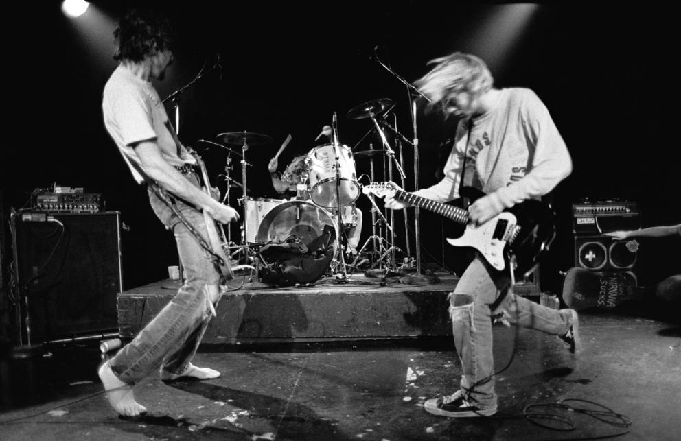 a black and white photo of the rock band Nirvana performing on stage