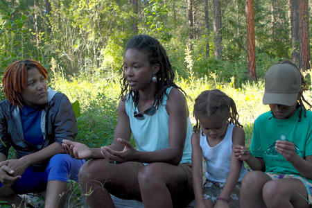 Two woman and two children sitting in the forest