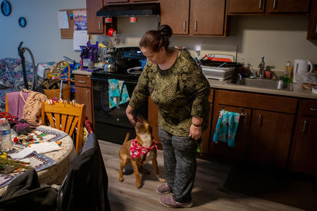 A woman plays with her dog in an apartment.