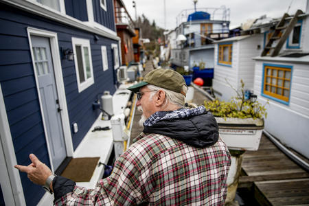 John Chaney walks from his houseboat through a row of other floating on-water residences at Seattle's Nickerson Marina