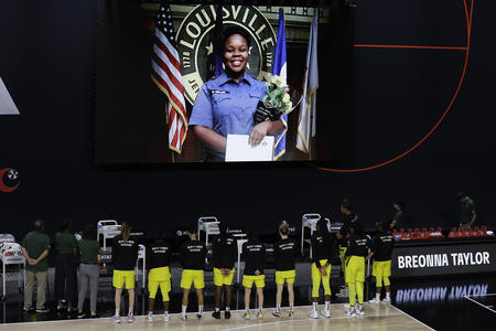 Seattle Storm players stand before a projected image of Breonna Taylor