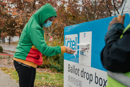 a voter drops their ballot in a drop box in Seattle