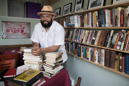 Estelita's Library owner, community organizer and activist Edwin Lindo stands along an array of books within the modest space in Seattle's Beacon Hill neighborhood, May 8, 2018. 