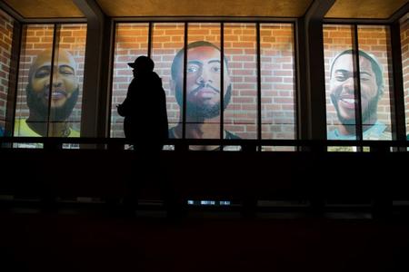 Man walks by portraits of formerly incarcerated black men