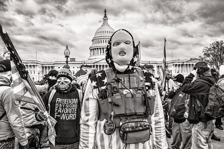 Black and white photo of person with a mask and protective gear in front of a crowd and the capitol building in Washington, DC