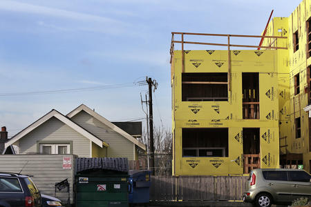 a single family home next to an unfinished multi-family home construction project