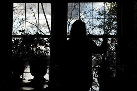A silhouette of a woman looking out a window