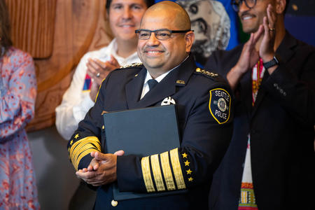A man in a seattle police chief uniform stands in a conference room