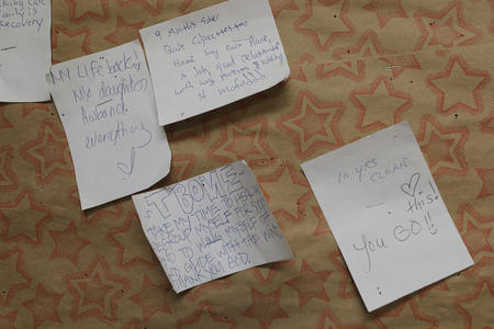 a close up of hand written notes pinned to a cork board