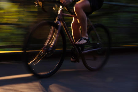 A quick shot of someone biking on a road, showing just the legs as they pedal
