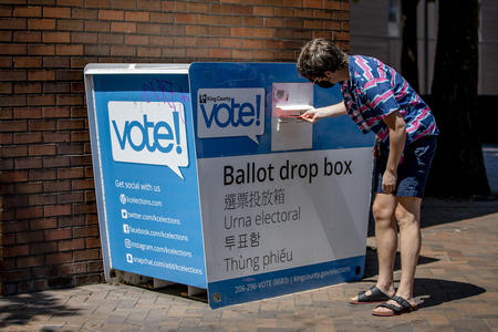 A voter drops a ballot off in a ballot drop box