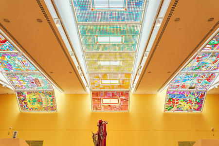 photo of a huge yellow room with stained glass panels running down the center and sides