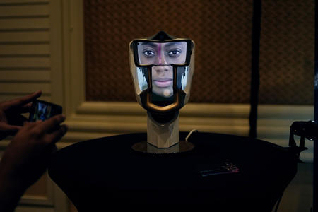 An artifically generated face is displayed on a robotic head.
