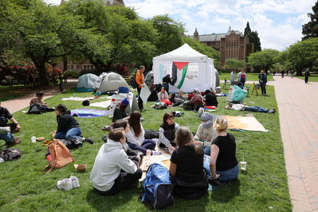 students sitting on the grass near tents on the UW campus