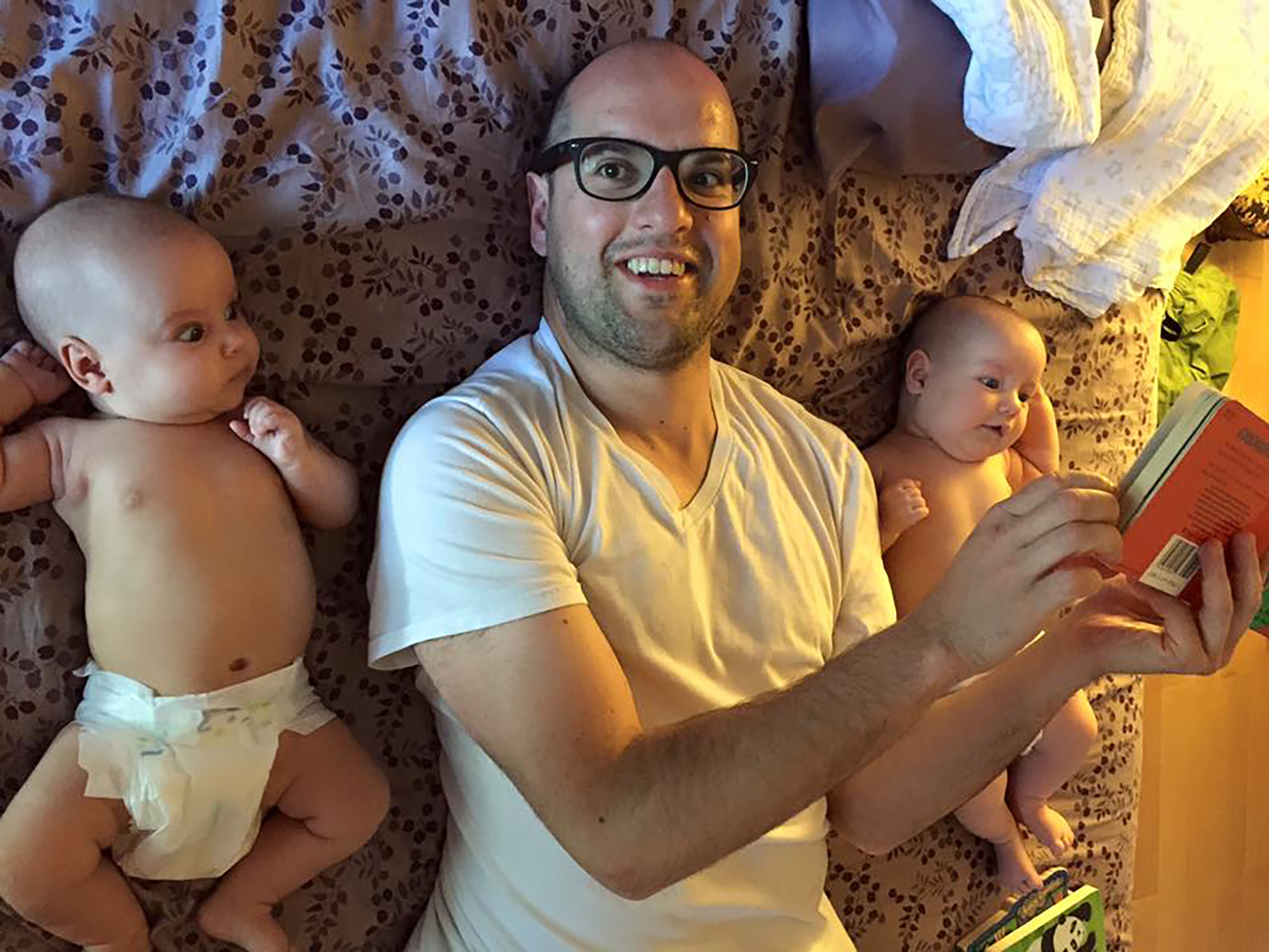 In this family photograph, Michael Clinard is pictured reading a children's book to his newborn twins in bed, during June 2015.