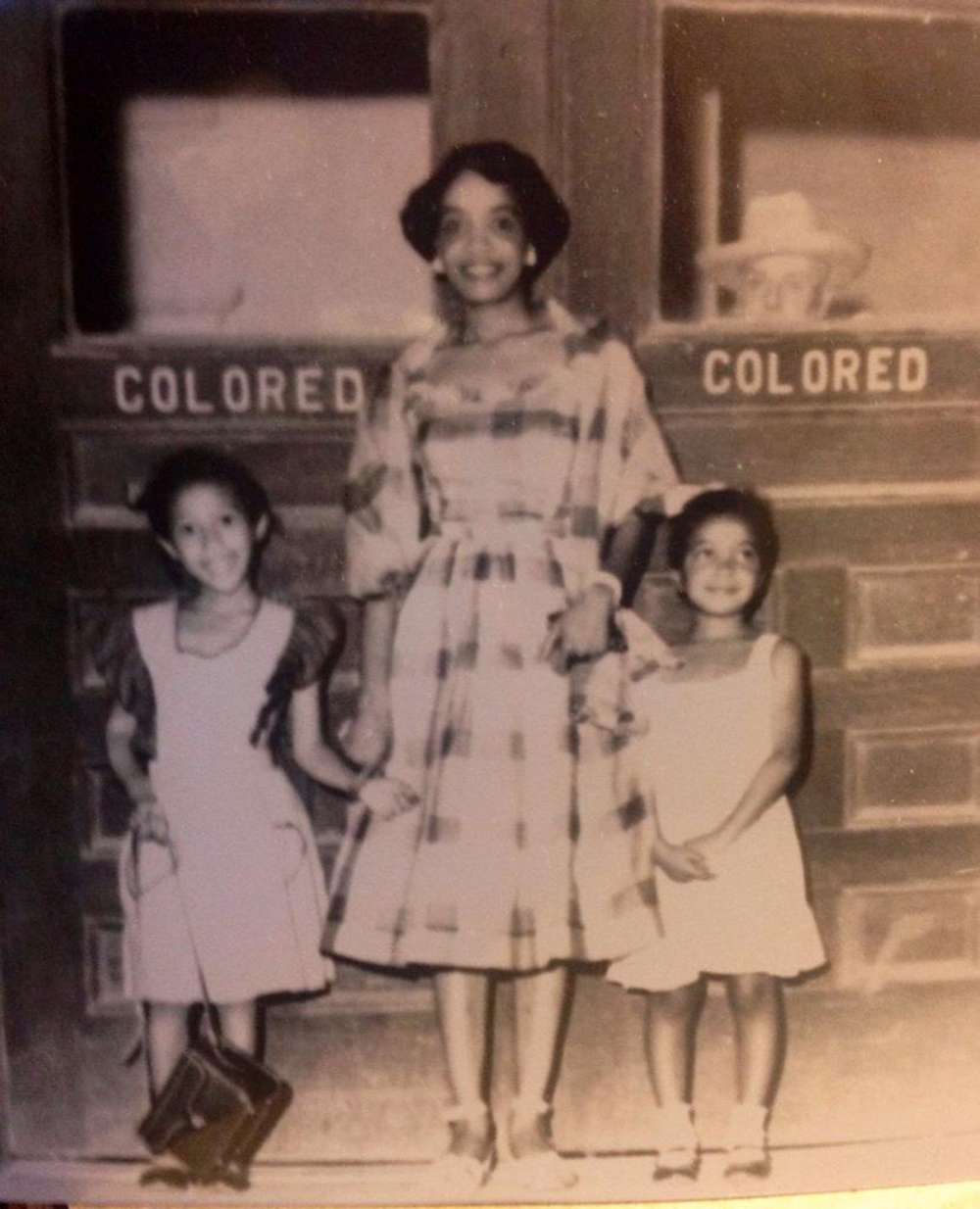 Mildred McHenry and two little girls in front of a 'Colored' sign