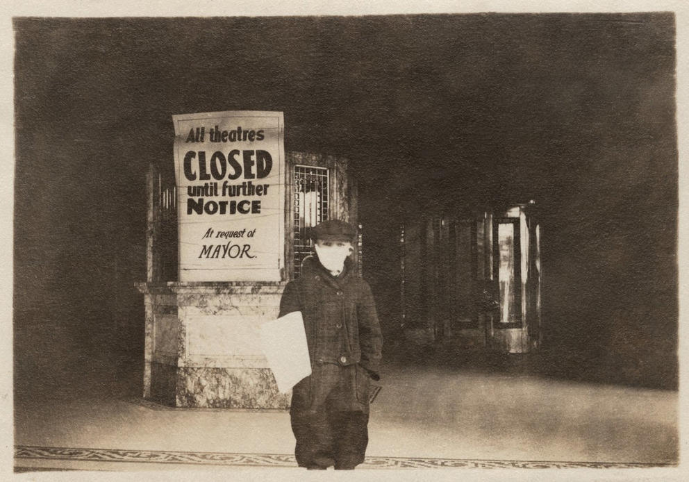 Boy in a mask in front of a closed theater.