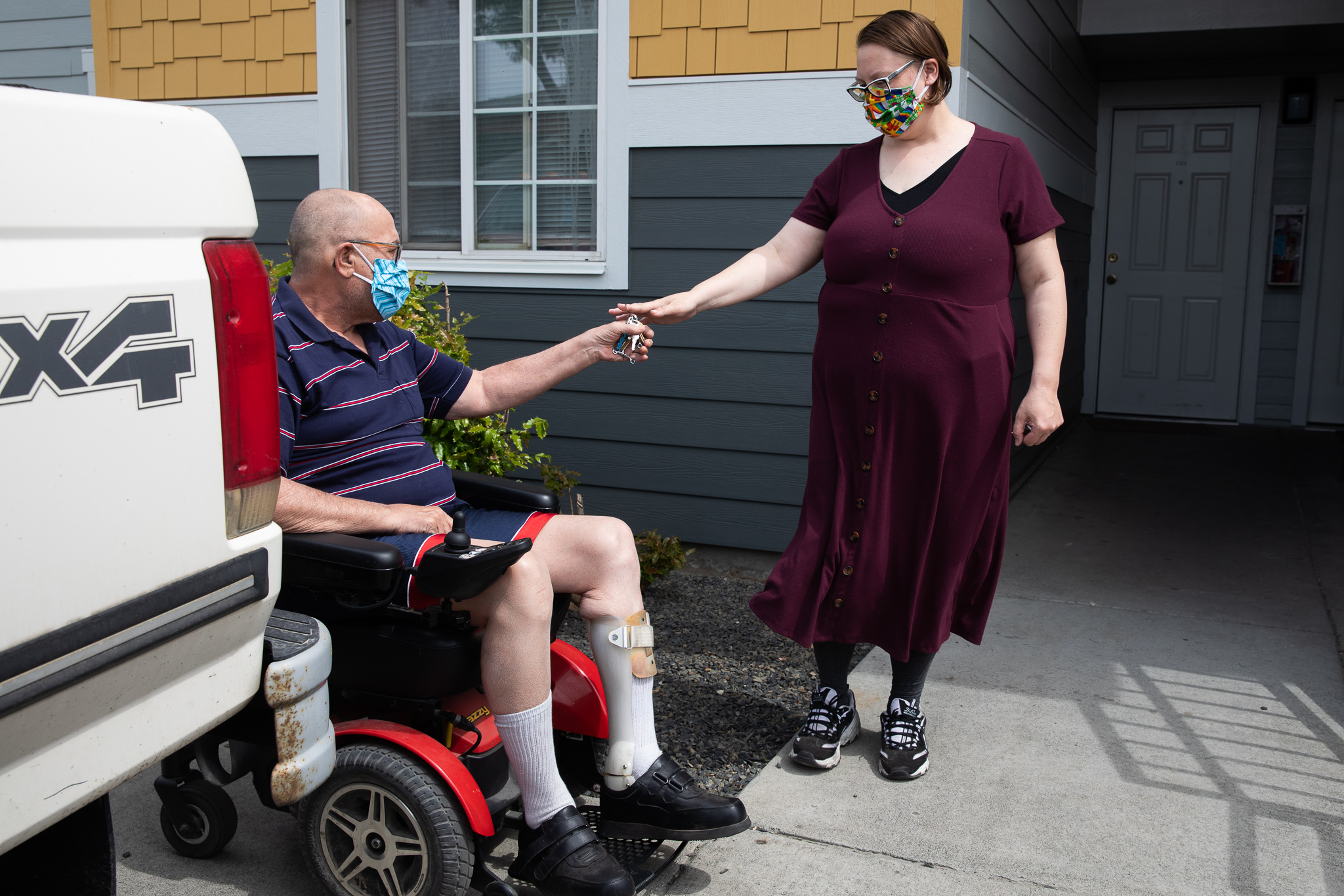 Desirae hands keys to Scott, who sits in a wheelchair