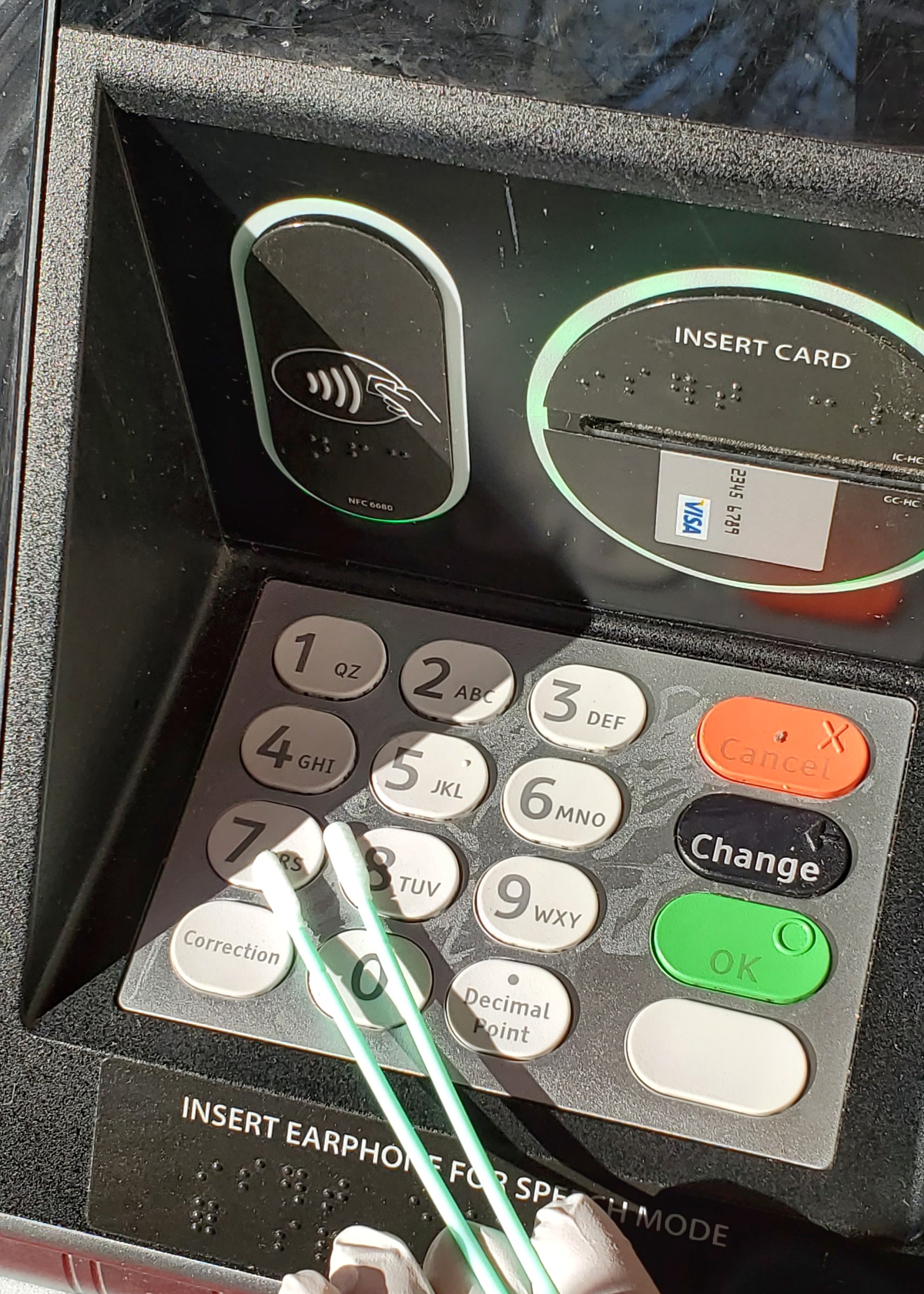 Hand holding swabs and swabbing an ATM keypad 